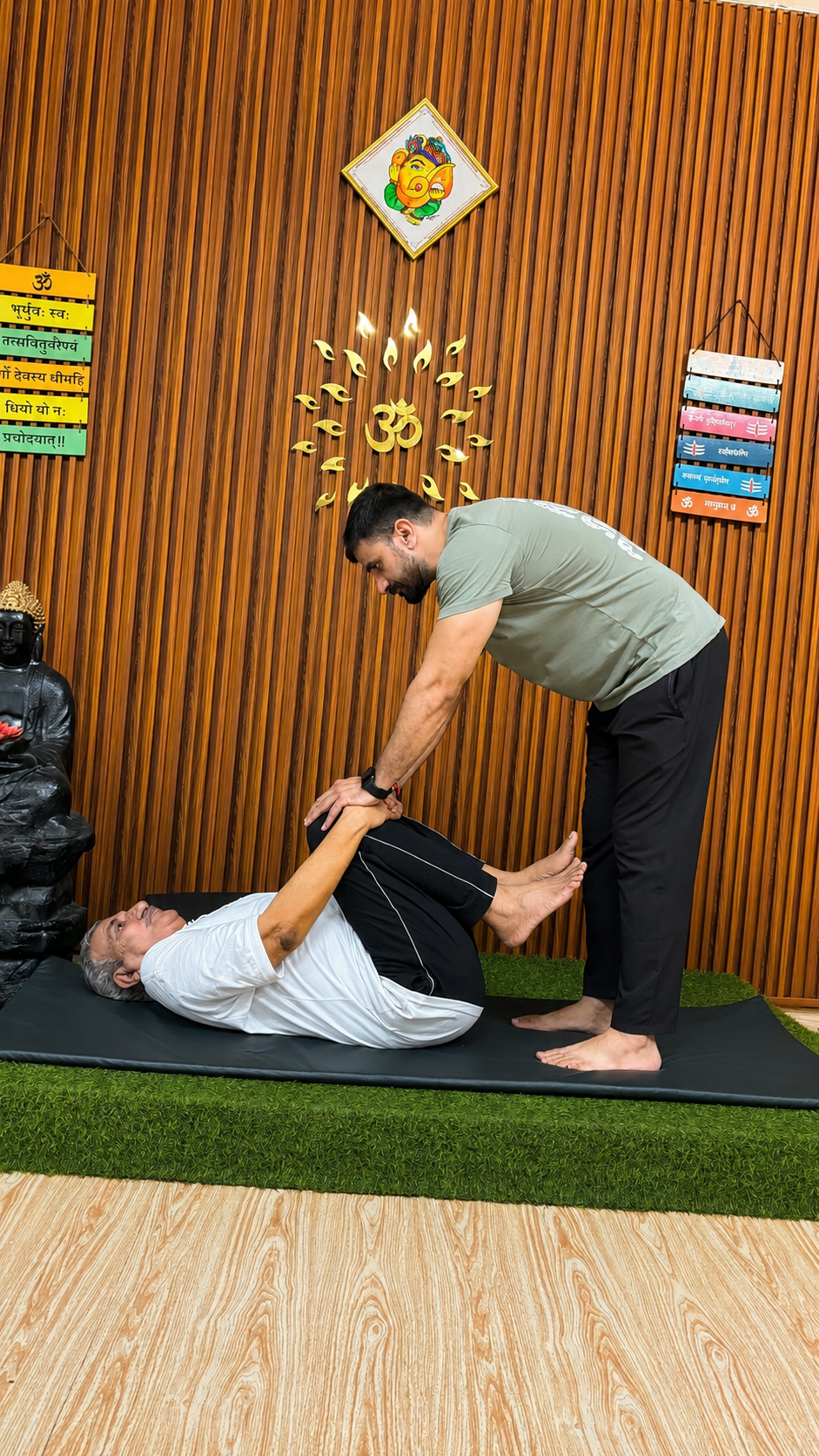 Sudhir assisting a senior student with a supine knee-to-chest stretch